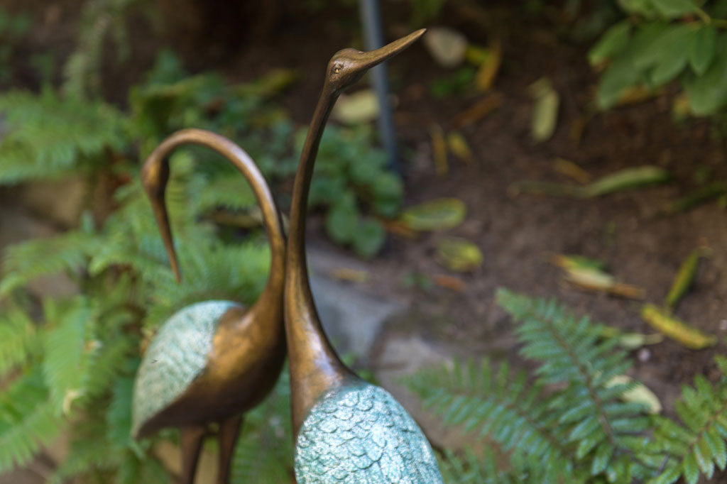 cast metal pair of cranes with blue detailing on feathers