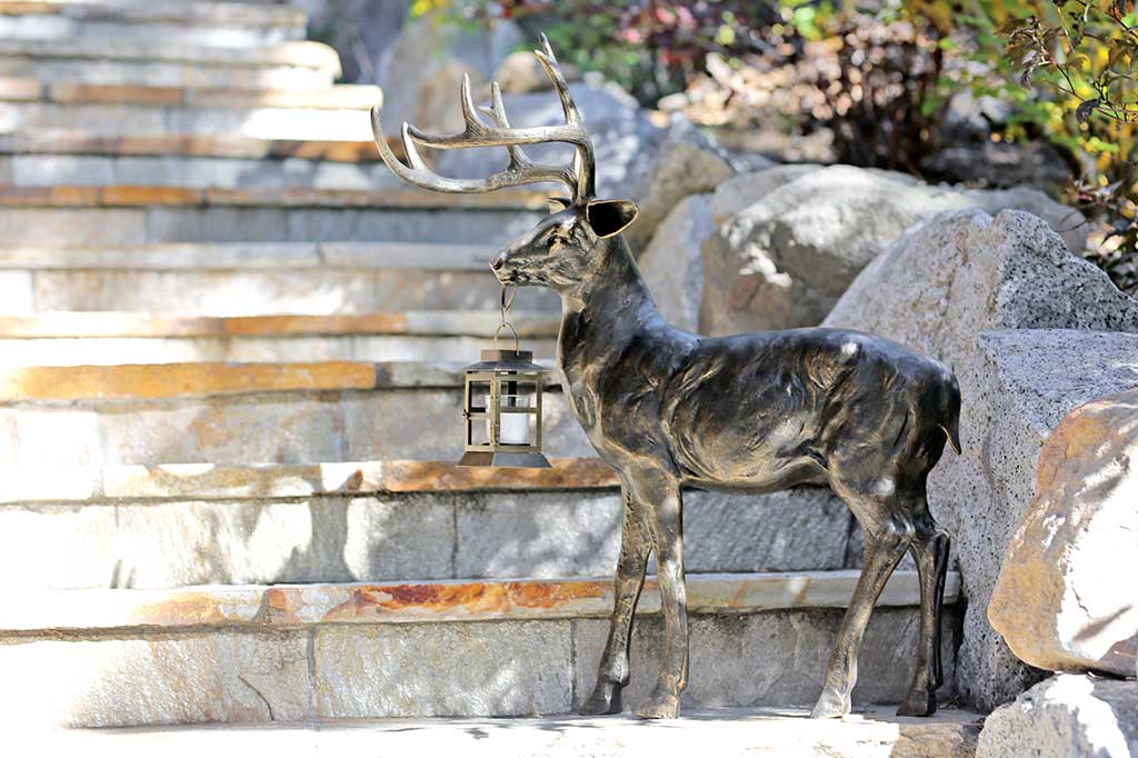 cast metal deer sculpture with a lantern illuminating outdoor pathways/stairs