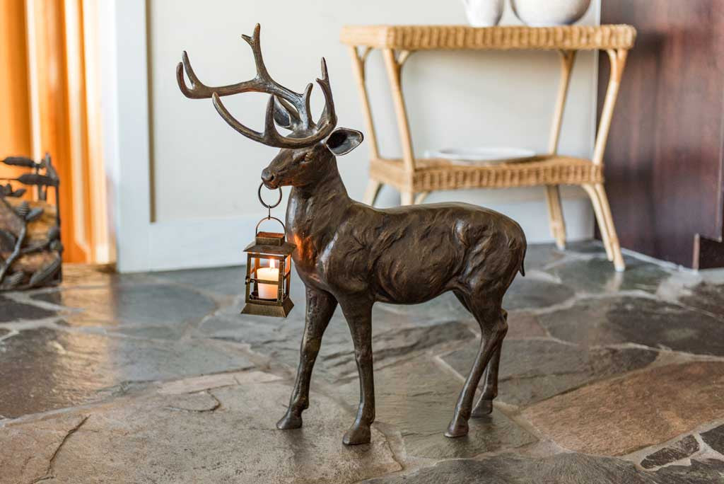 cast metal deer with lantern in mouth set indoors in a cabin