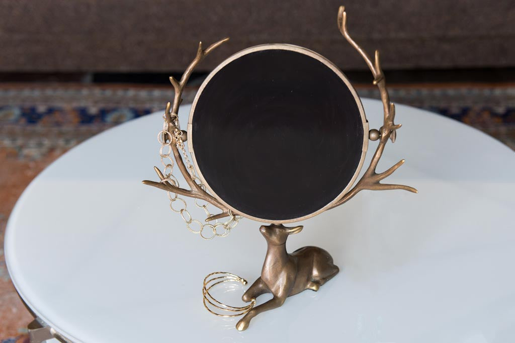 vanity mirror supported by resting deer whose antlers frame the mirror