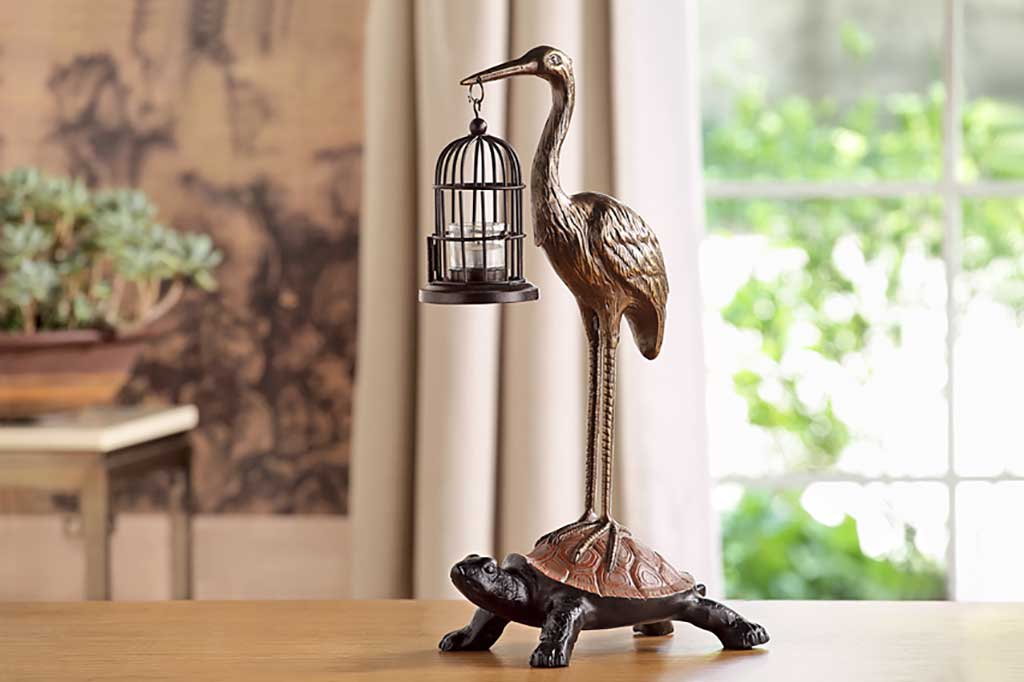 Garden sculpture of crane holding bird cage lantern, standing on a turtle's back - placed in living room with asian theme decor