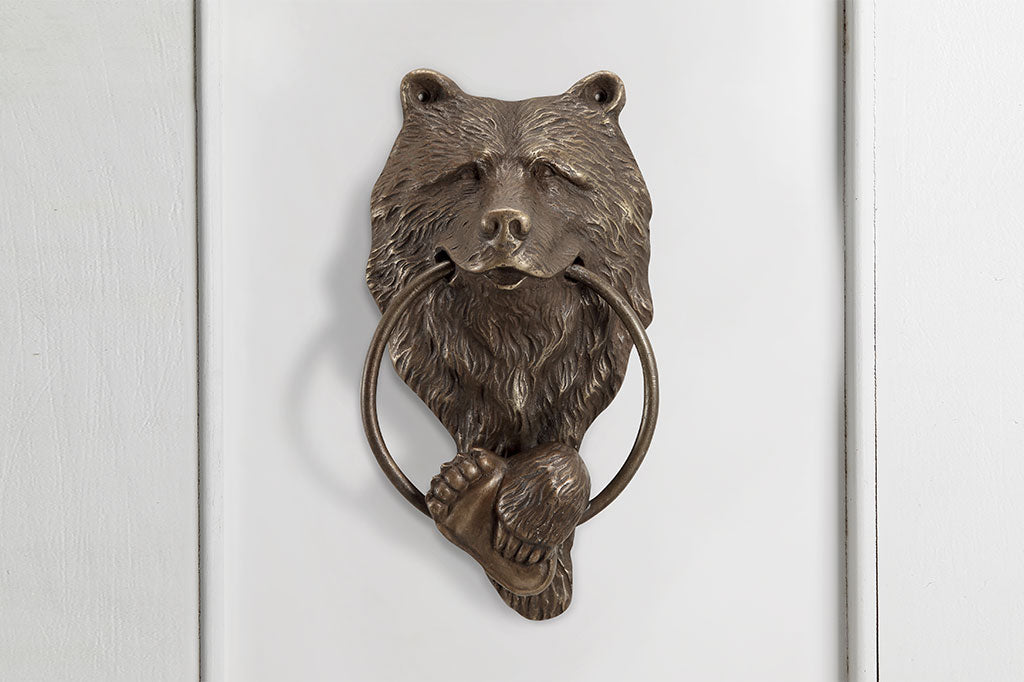 cast metal bear door knocker with the ring inside the bears mouth shown on wall