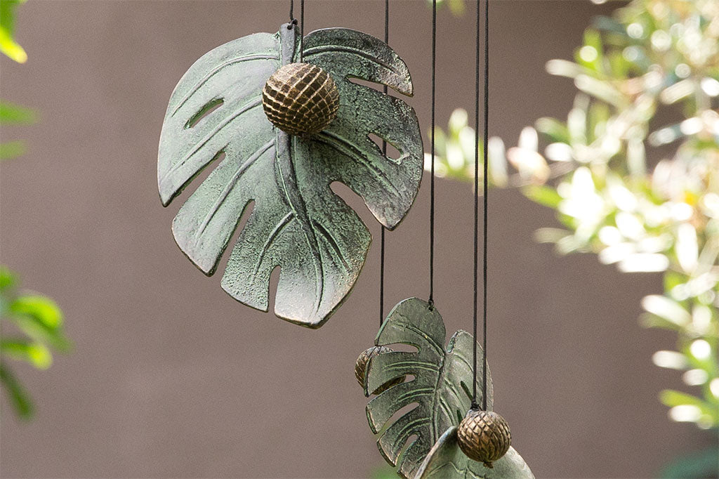 Detailed view of cast metal monstera leaf, gray with blue patina coloring. Ball knocker a bronzy color with lattice detail