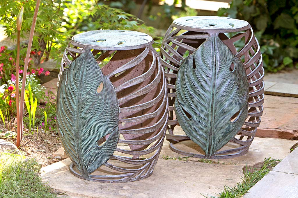 palm leaf motif shown on two matching garden stools in tropical theme yard