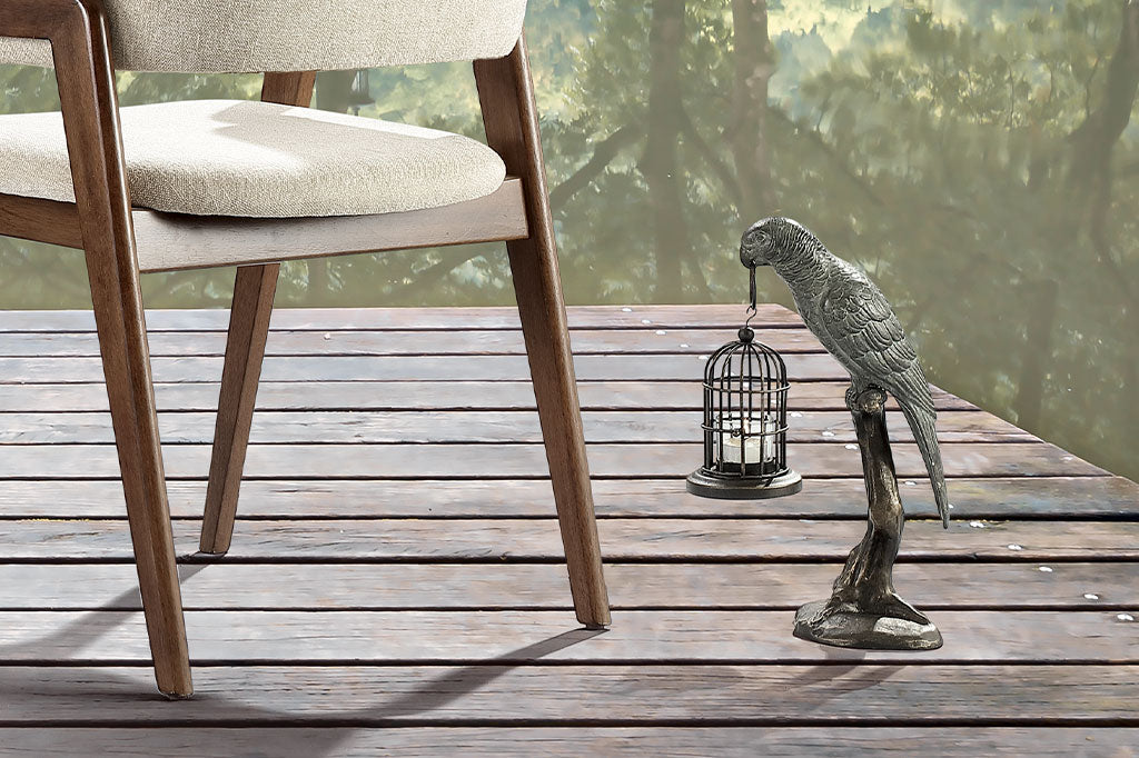 cast metal parrot on a branch holding on a lantern that holds a tealight sculpture
