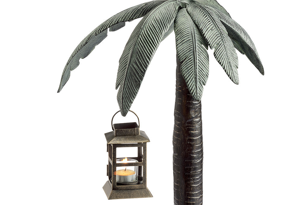 close up view of cast metal palm tree and lantern hanging from branch