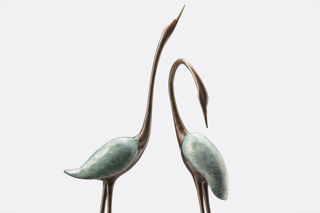 two crane sculptures with marble base have swirly verdigris finish