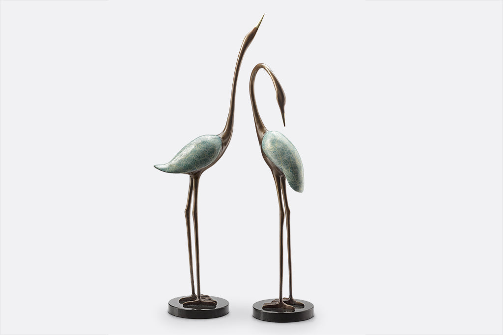 two crane sculptures with marble base have swirly verdigris finish