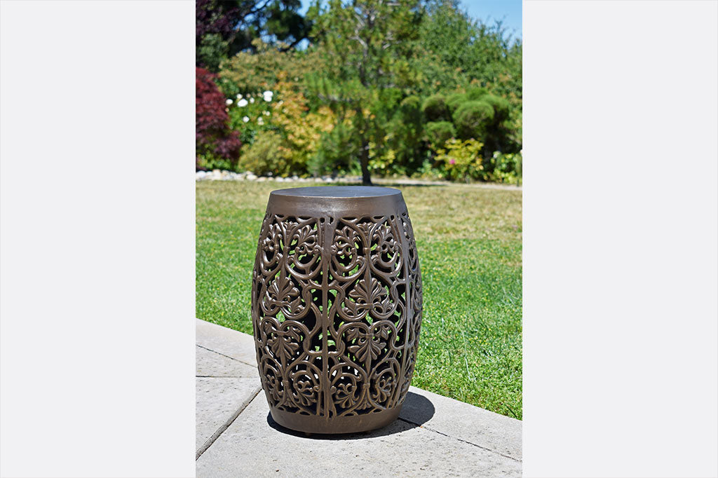 Elaborate floral scrollwork around a garden stool placed near lawn