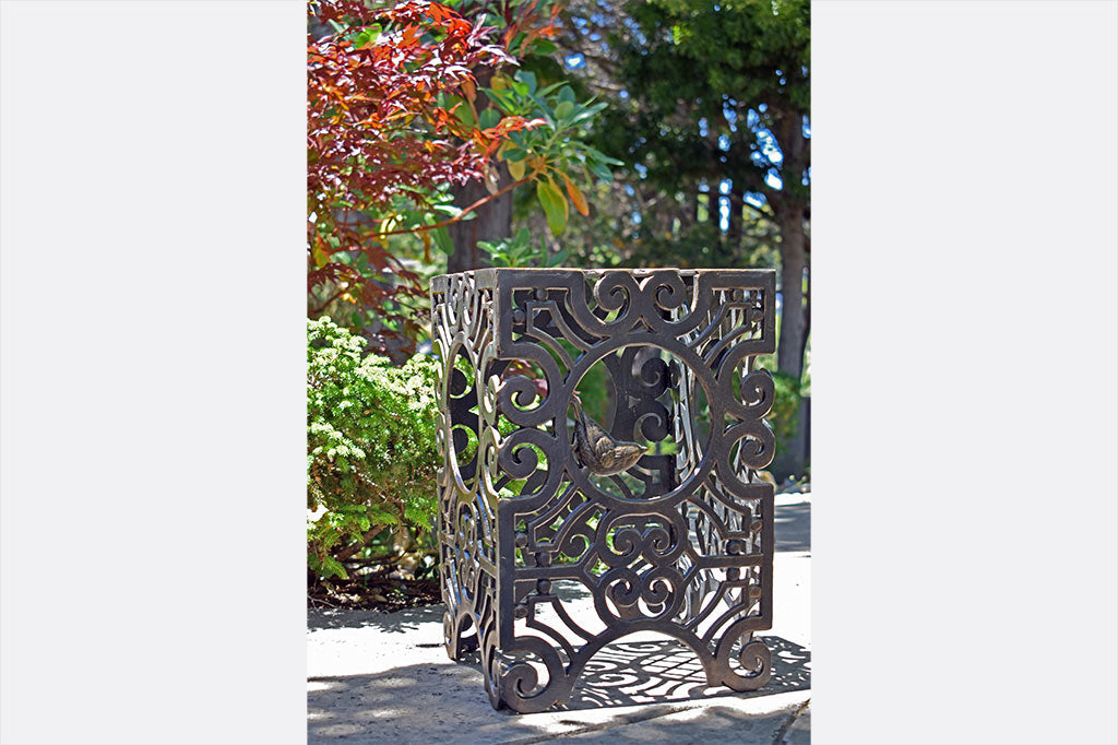 Rectangular stool featuring Capistrano scrollwork and swallow bird sculpted in circular opening shown on pavement in backyard setting
#color_Espresso Bronze
