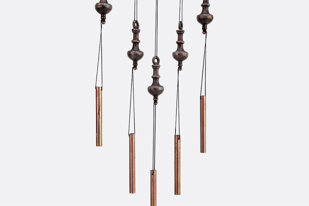 hanging sculpture of rods and tops suspended from branch motif