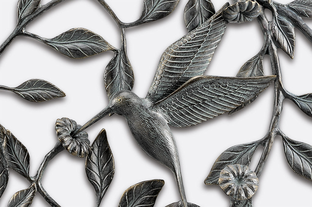 closup of hummingbird sipping from a blossom on a sculptural wall plaque