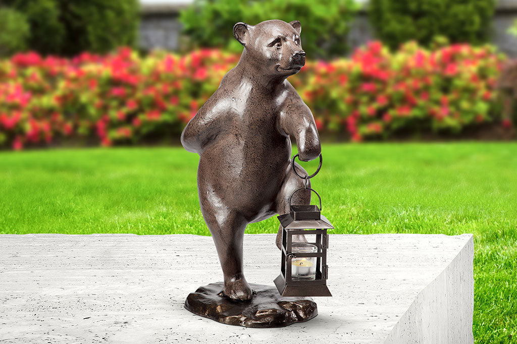 Set on concrete bench in garden, Garden bear holds lantern and picks up right foot mid-step