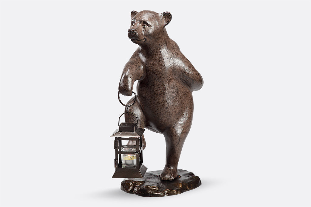 Garden bear holds lantern and picks up right foot mid-step