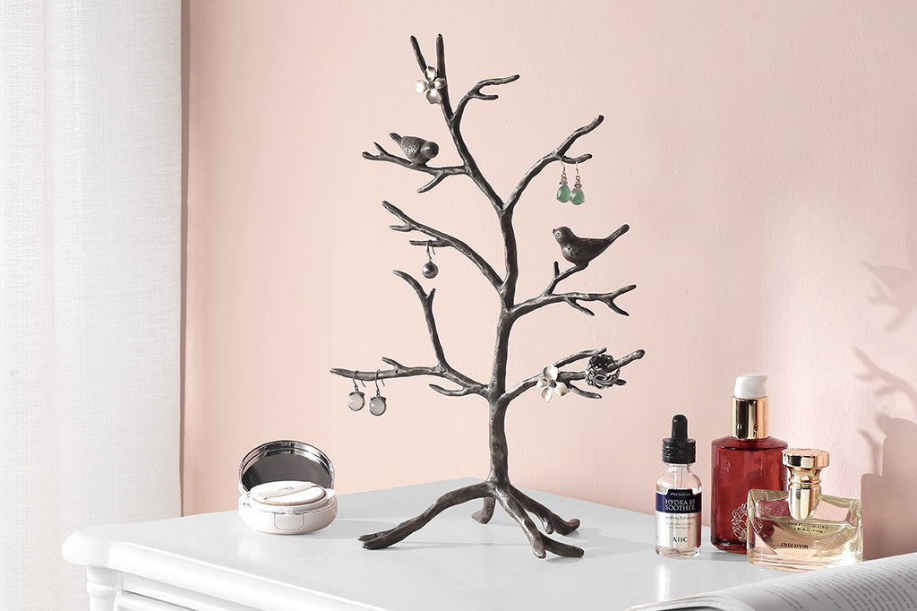 tree shaped jewelry stand holding earrings shown on vanity table in pink room