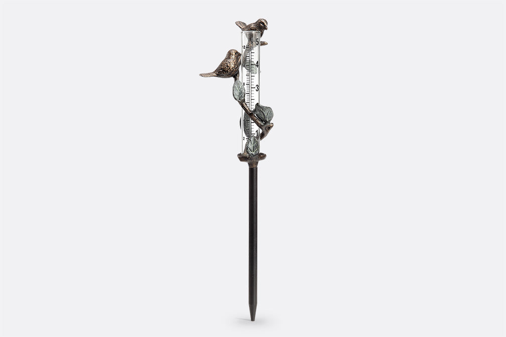cast metal with leaf and branch with bird surrounding glass beaker staked rain catcher