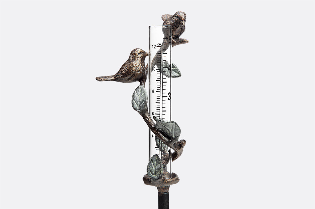 cast metal with leaf and branch with bird surrounding glass beaker staked rain catcher