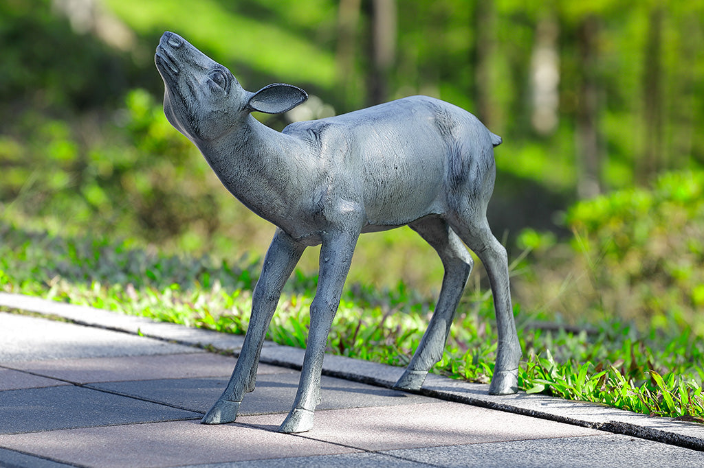 zinc finish on sculpted garden art of doe; shown on sidewalk near woods