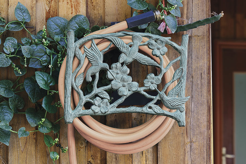 bird and dogwood branches adorn a wall-mounted garden hose holder