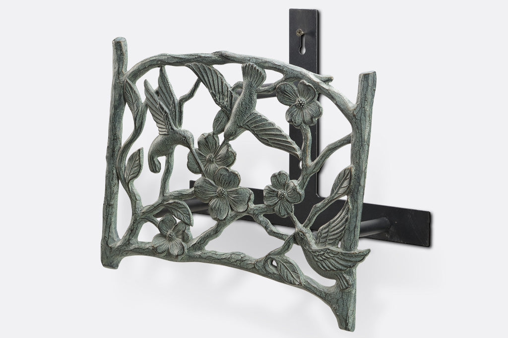bird and dogwood branches adorn a wall-mounted garden hose holder