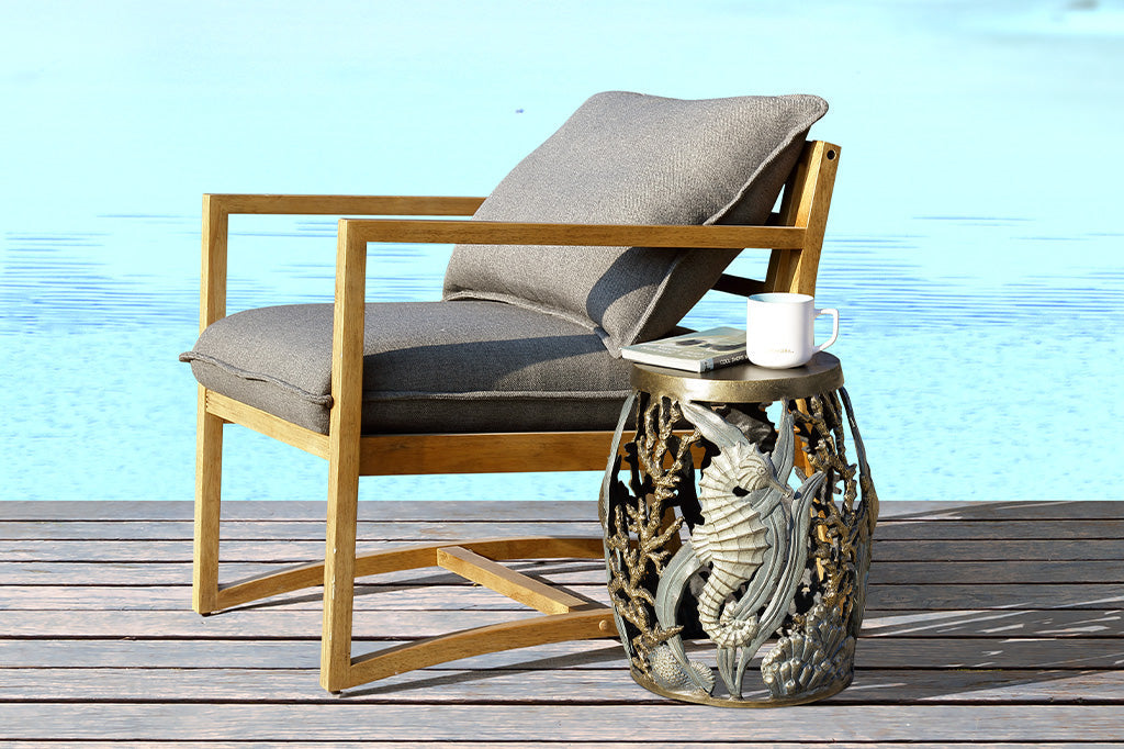 cast metal garden stool with solid seat, design of tidal animals: kelp, coral, turtle, seahorse in various finishes of green, blue, bronze, and zinc; shown by pool and wood chair