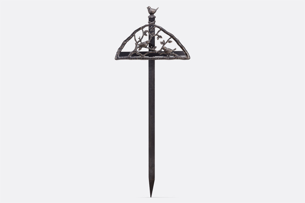 Garden staked hose holder features a decorative bird and branch hose screen, bird finial on stake