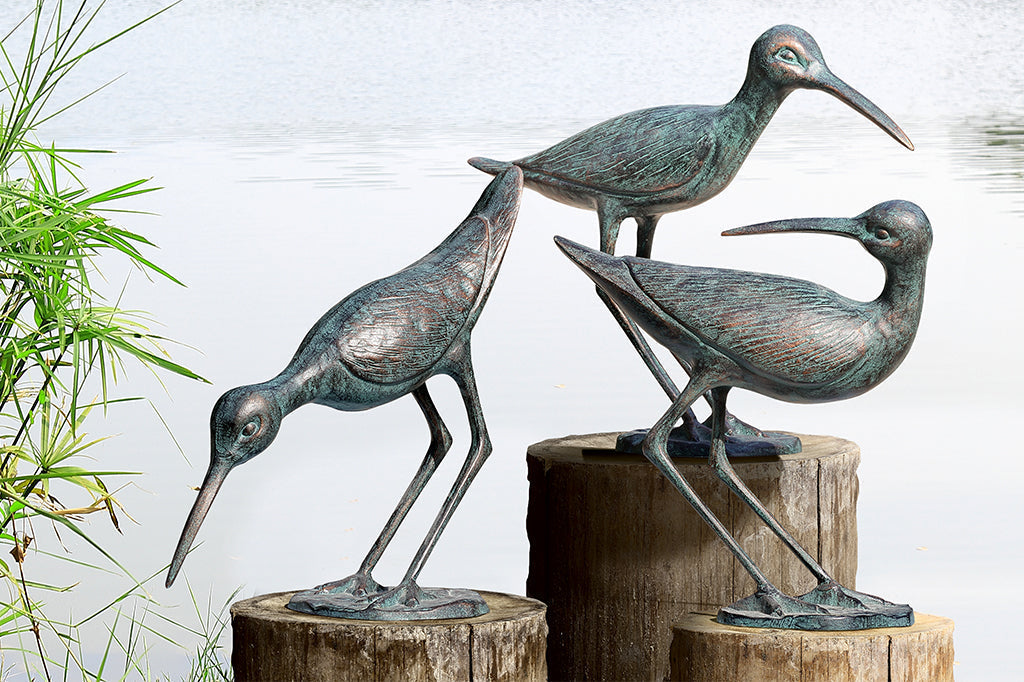 Set of three cast metal sandpiper sculptures set by the water
