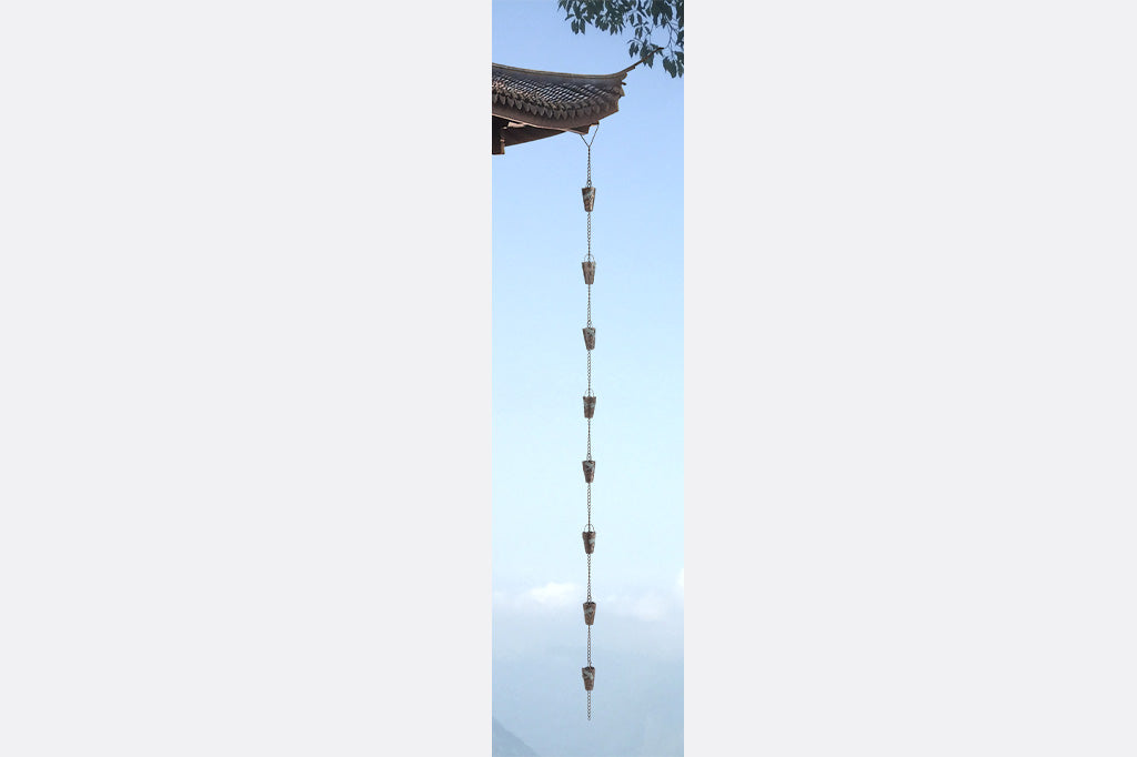 view of all 8 rain cups featuring a dragonfly motif on a rain chain attached to Asain style roof