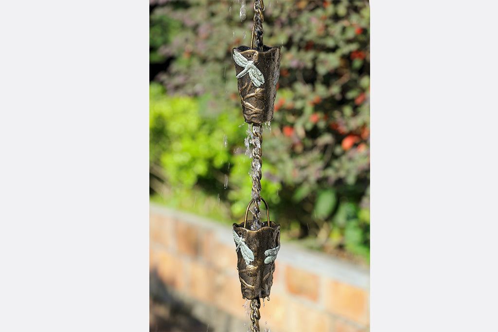 water cascades over two rain cups on a dragonfly motif rain chain shown outside on sunny day
