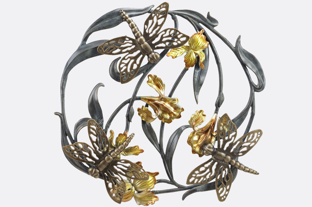 Three dragonflies on a circular iris motif in a cast metal wall art sculpture; irises are bright golden yellow