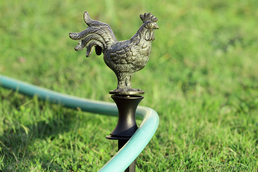 rooster shaped bronze finish hose guard shown with grass and hose