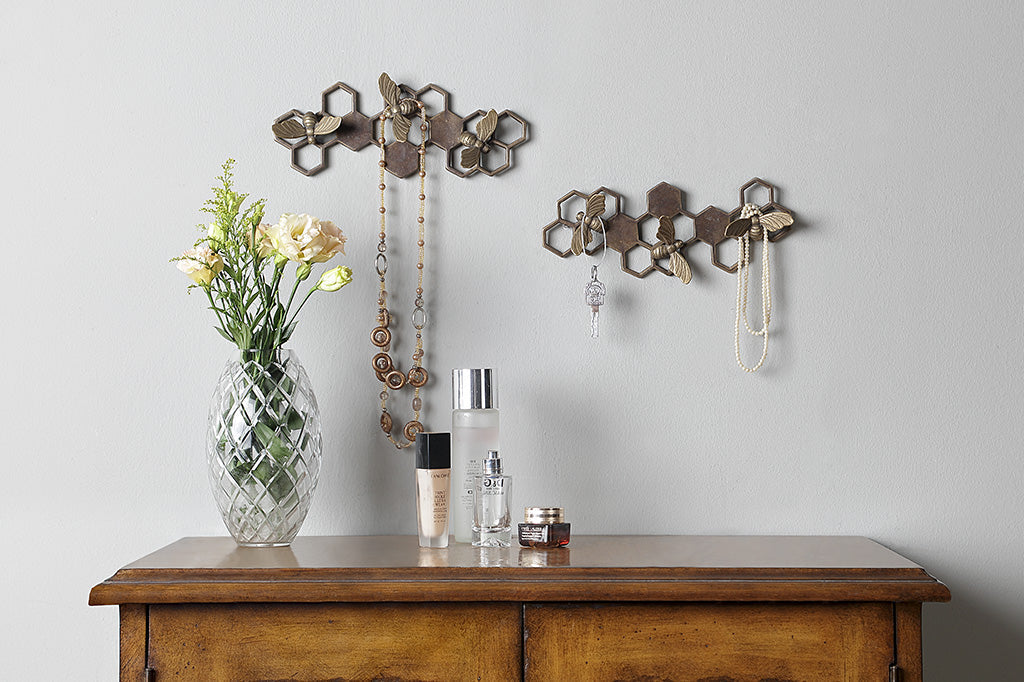 Brass wall art key hook showing honeycomb and bee motif, two sets shown on wall above bedroom dresser