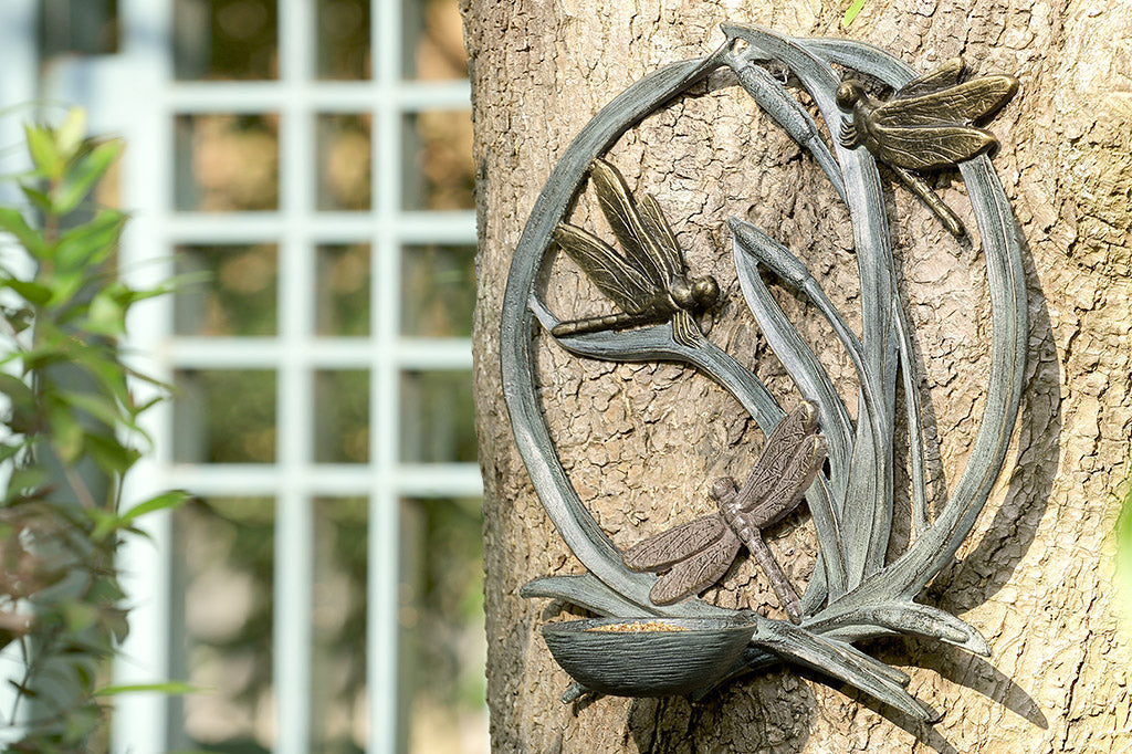 birdfeeder station that hangs on walls with dragonfly and cattail motif shown hung on tree trunk