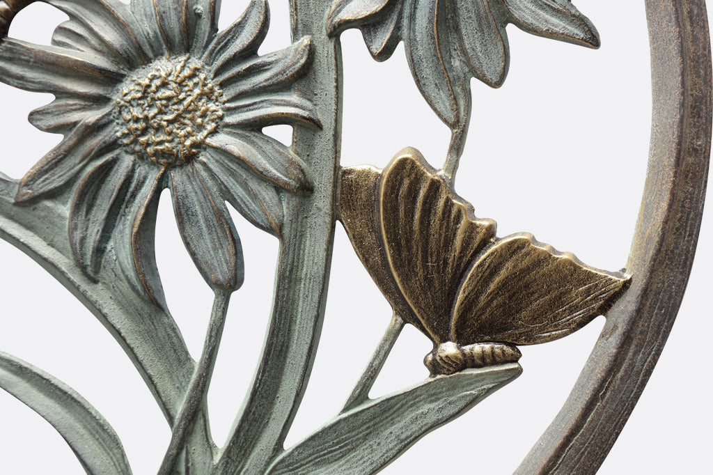 close up detail of blossoms on a wall mounted cast metal bird feeder