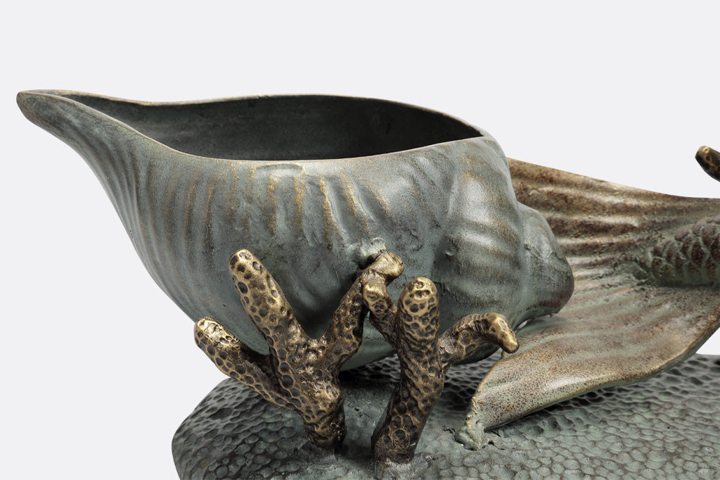 Closeup detail of planter shaped like shell on the base, near sculpted coral