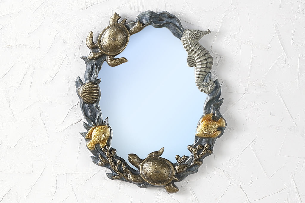 cast metal mirror with sea creatures and shells on rim, seahorse, turtle, fish and coral surrounding the mirror. Set on indoor wall