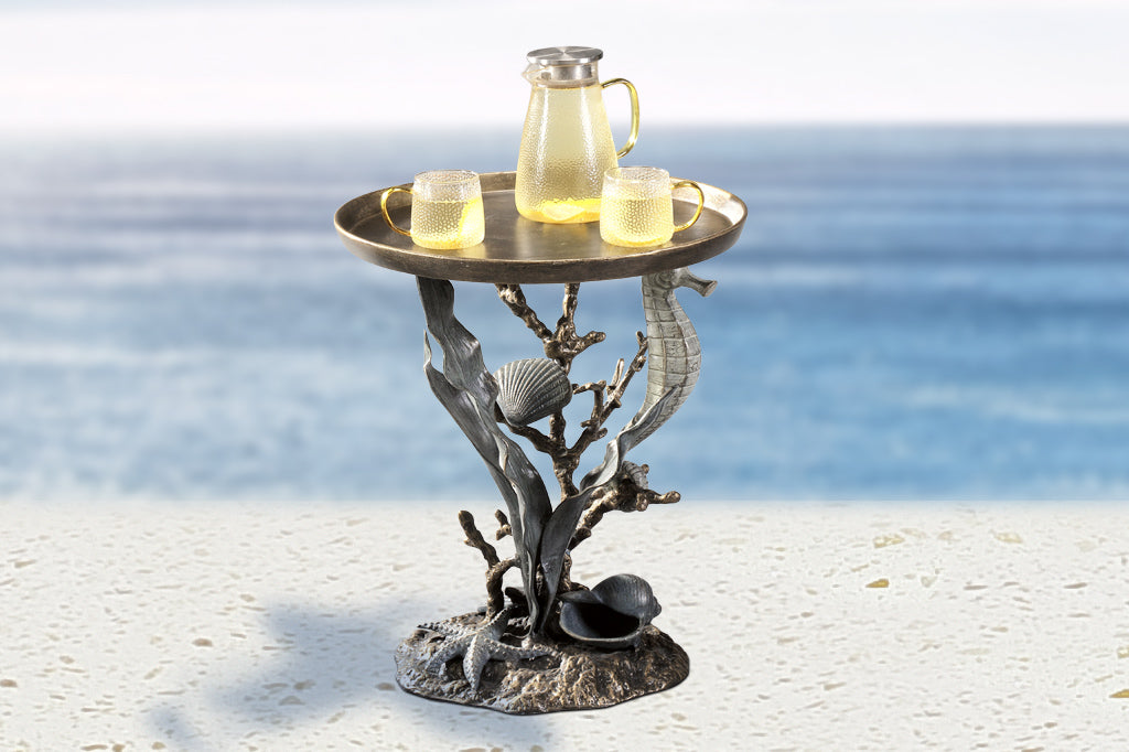 accent table with coral reef sculpted base design: seahorse, coral, scallop and nautilus shells, seastar, kelp - shown holding lemonade pitcher and glassware