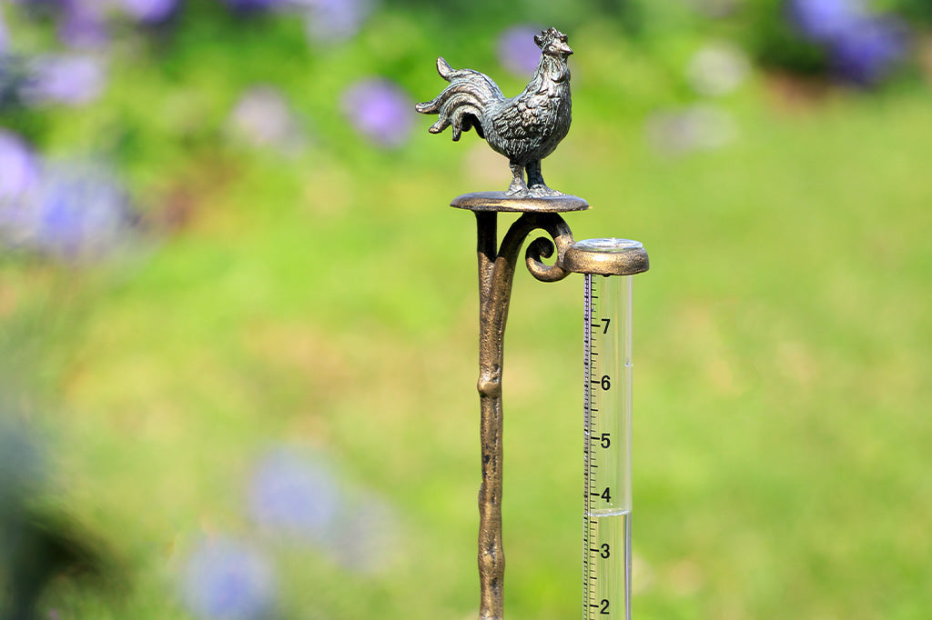 Rooster finial on staked rain catcher shown in garden