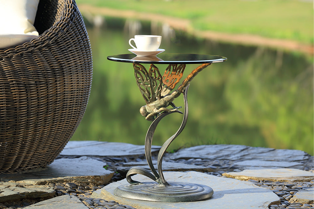 cast metal dragonfly accent table with glass top set in outdoor scene