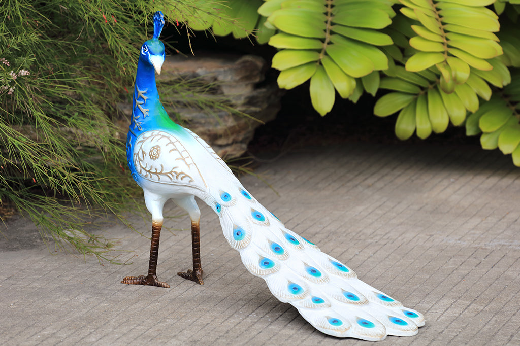 white and blue peacock sculpture shown in gardn