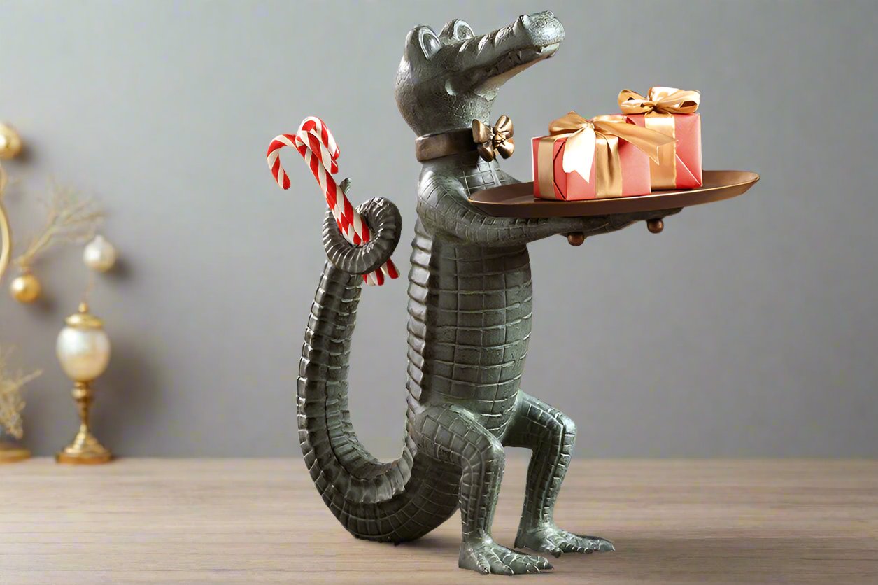 Holiday décor: Standing Crocodile dressed as a butler holds a serving tray whilst hiding candy canes behind its back. Shown in studio setting with gold holiday decor