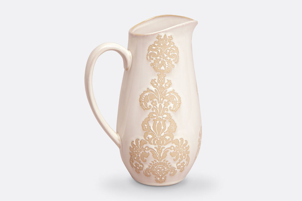 White ceramic vessel with blush on white, lace-inspired embossed design shown on a water pitcher
