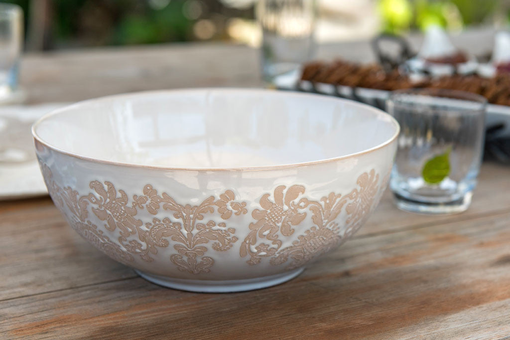 White ceramic vessel with blush on white, lace-inspired embossed design shown on abowl