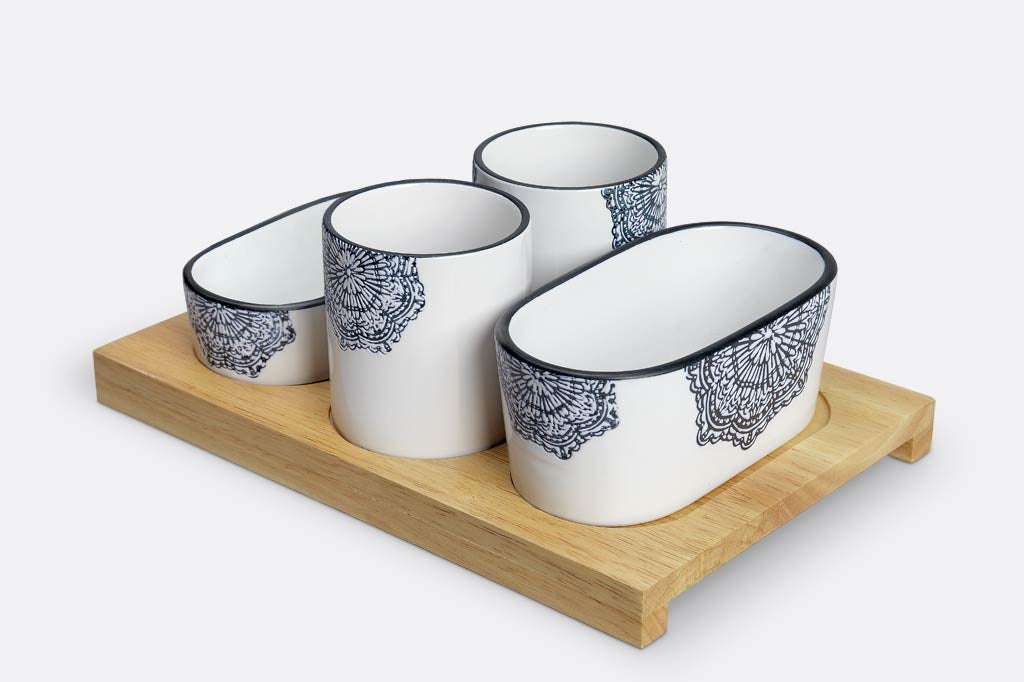 white ceramic serving vessels on wood tray; they have blue mediterranean glazed print and blue rims