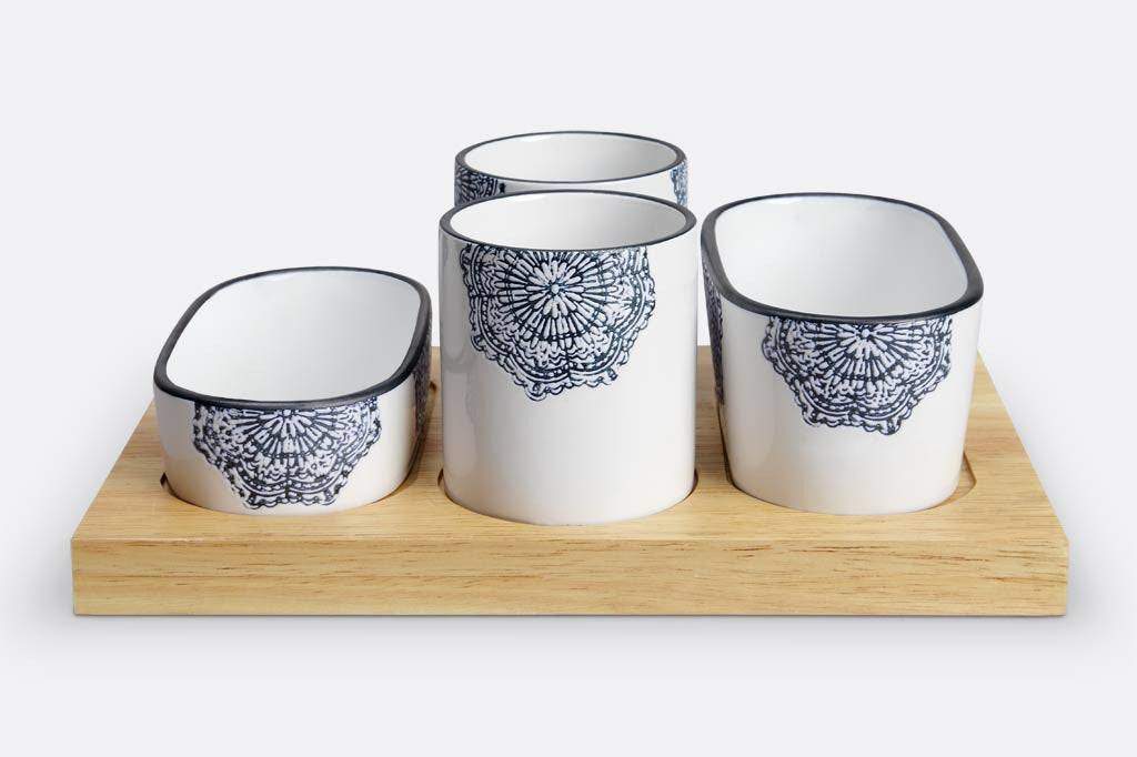 white ceramic serving vessels on wood tray; they have blue mediterranean glazed print and blue rims