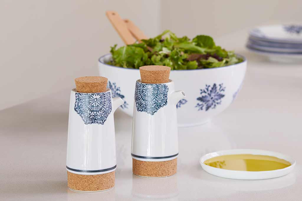 salt and pepper shaker shown by salad scene. white ceramic with blue mediterranean glazed print and blue stripe at base