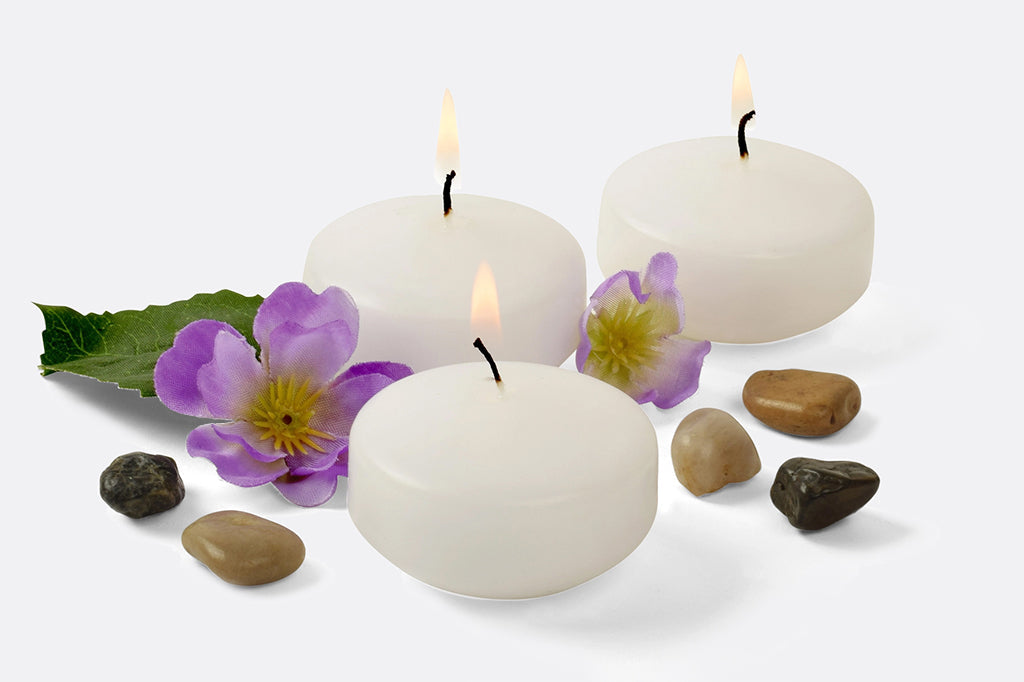 three floating tealights surrounded by flowers and pebbles, giving a spa like atmosphere