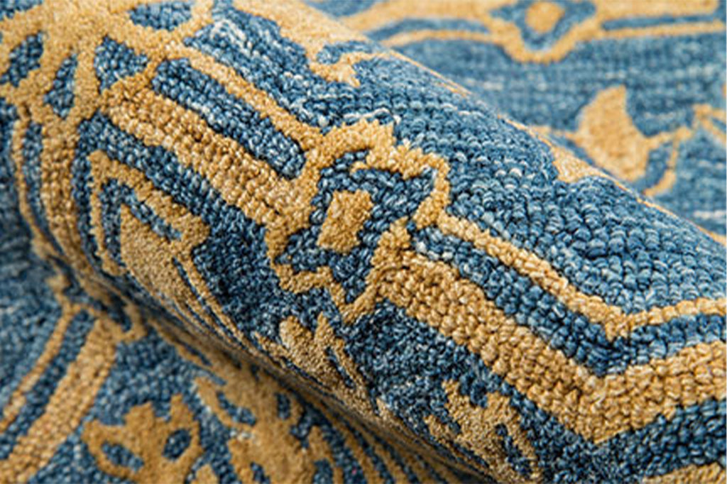 close up detail of texure: Moroccan inspired arabesques and medallions on hooked wool rug in slate blue and golden tan colors