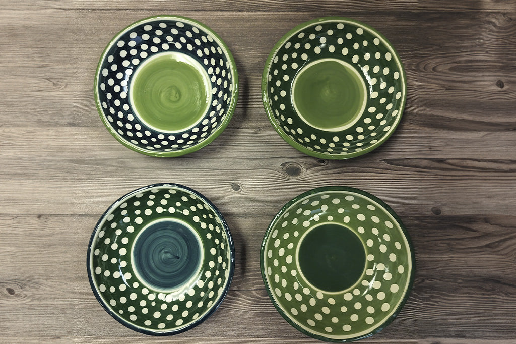 Set of four dark green with white polka dot soup bowls , top view on a dark wood table