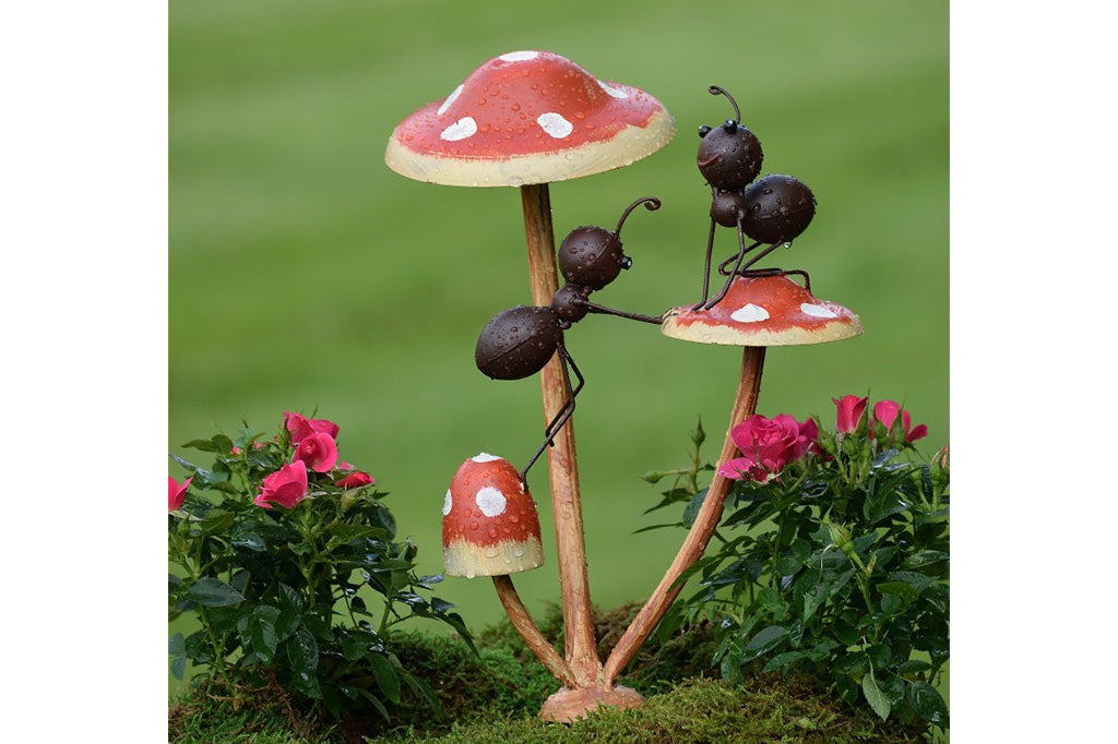 Metal garden accent of two ants frolic on a trio of mushrooms.